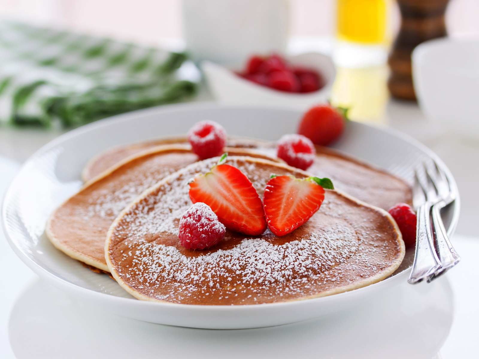 Оладьи на тарелке с сахарной пудрой и ягодами клубники