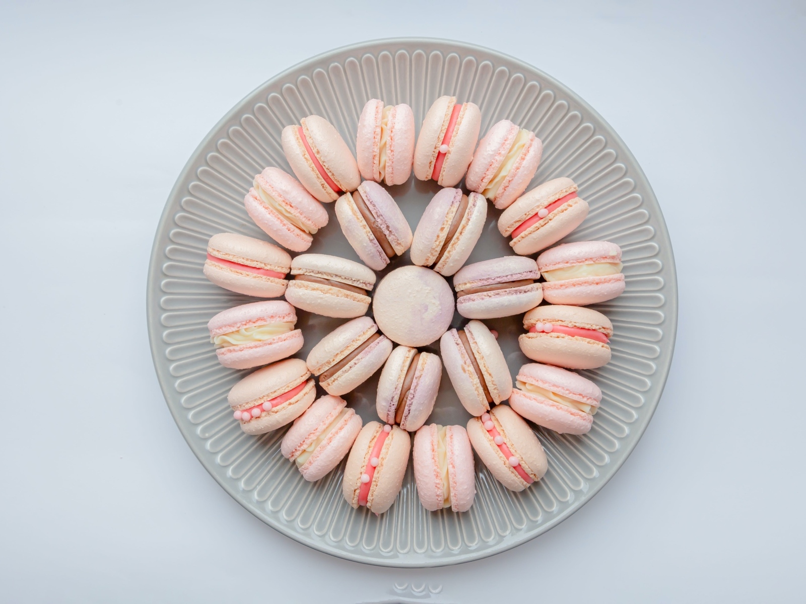 Розовый десерт макарон на большой тарелке