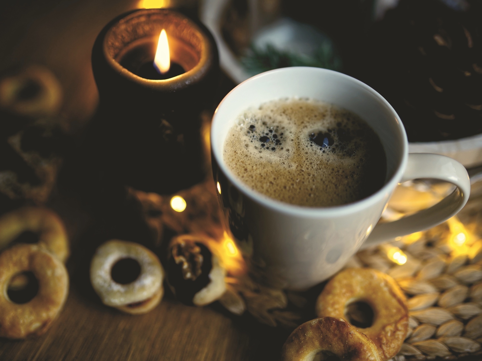 Чашка кофе на столе со свечой и печеньем