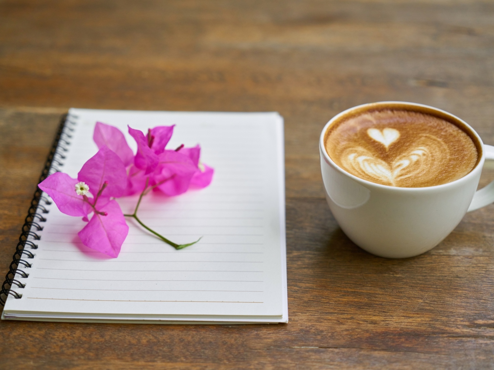 Чашка кофе на столе с блокнотом и цветами