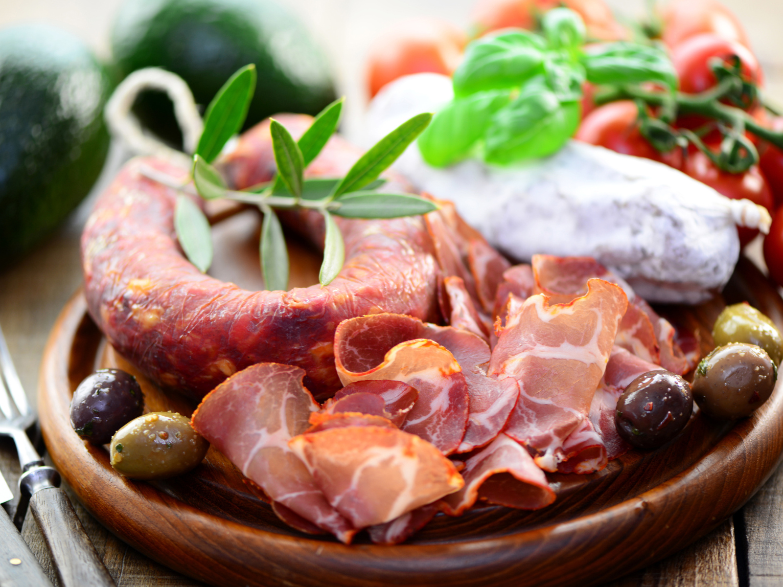 Колбаса, ветчина и оливки на деревянной тарелке