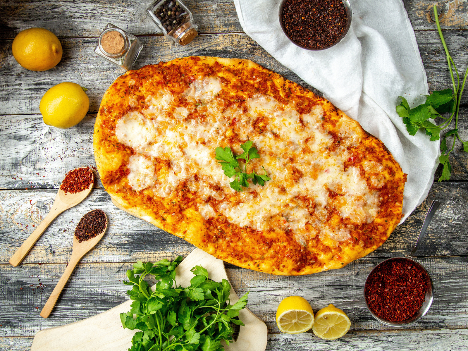 Пицца на столе с лимонами и пряностями