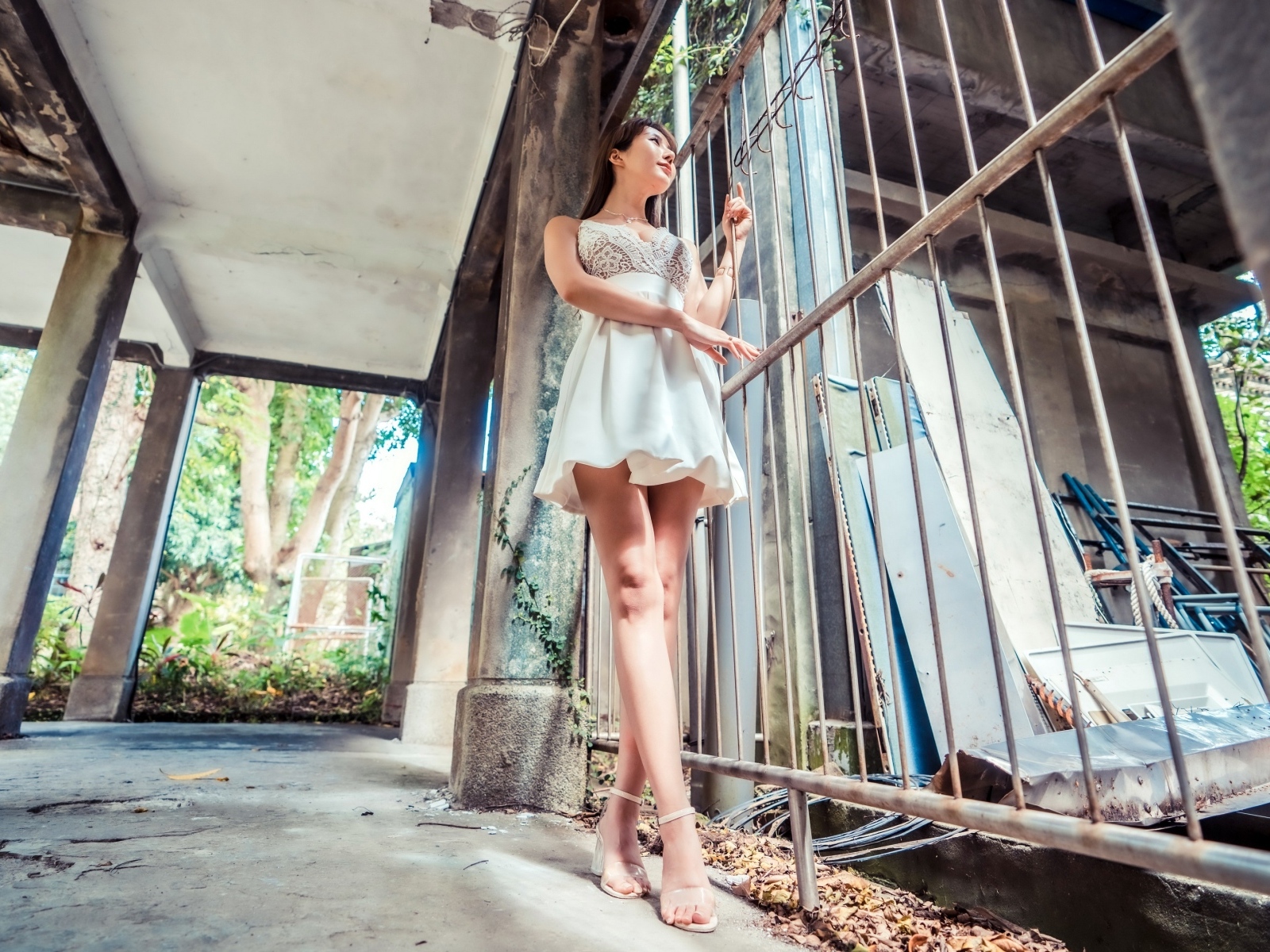 Девушка азиатка в платье стоит у решетки 