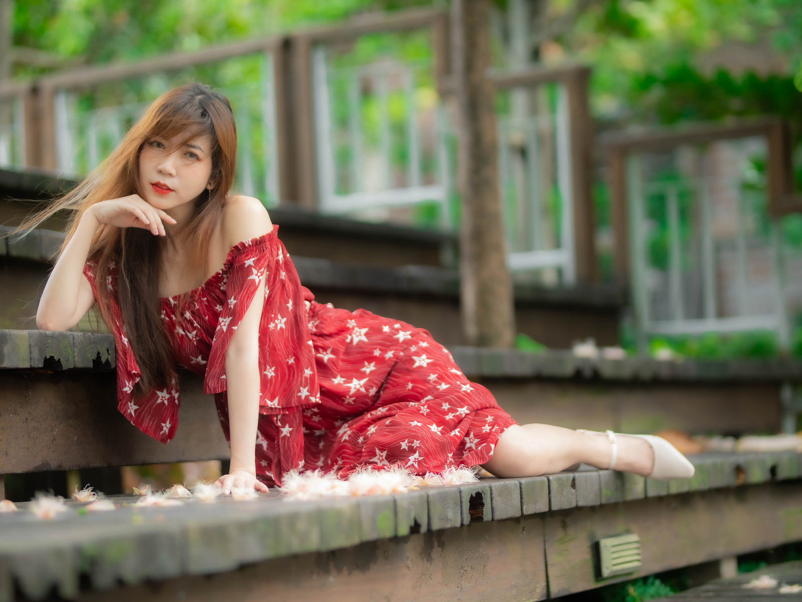 Девушка азиатка лежит на ступеньках в красном платье