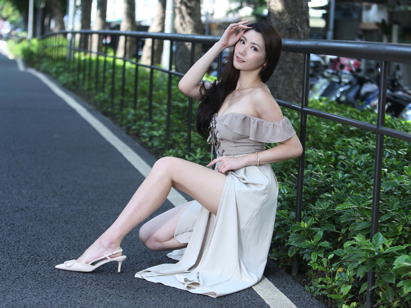 Девушка азиатка сидит у забора