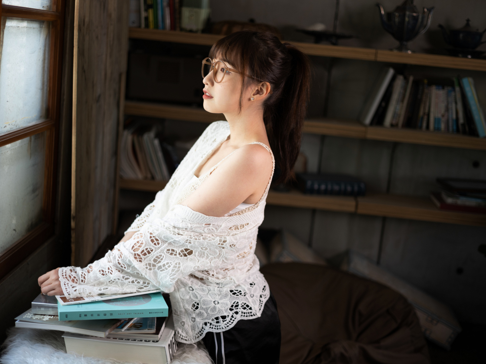 Девушка азиатка с книгами у окна