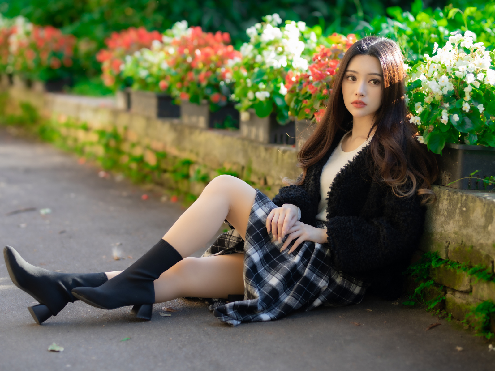Азиатка сидит на асфальте у цветов