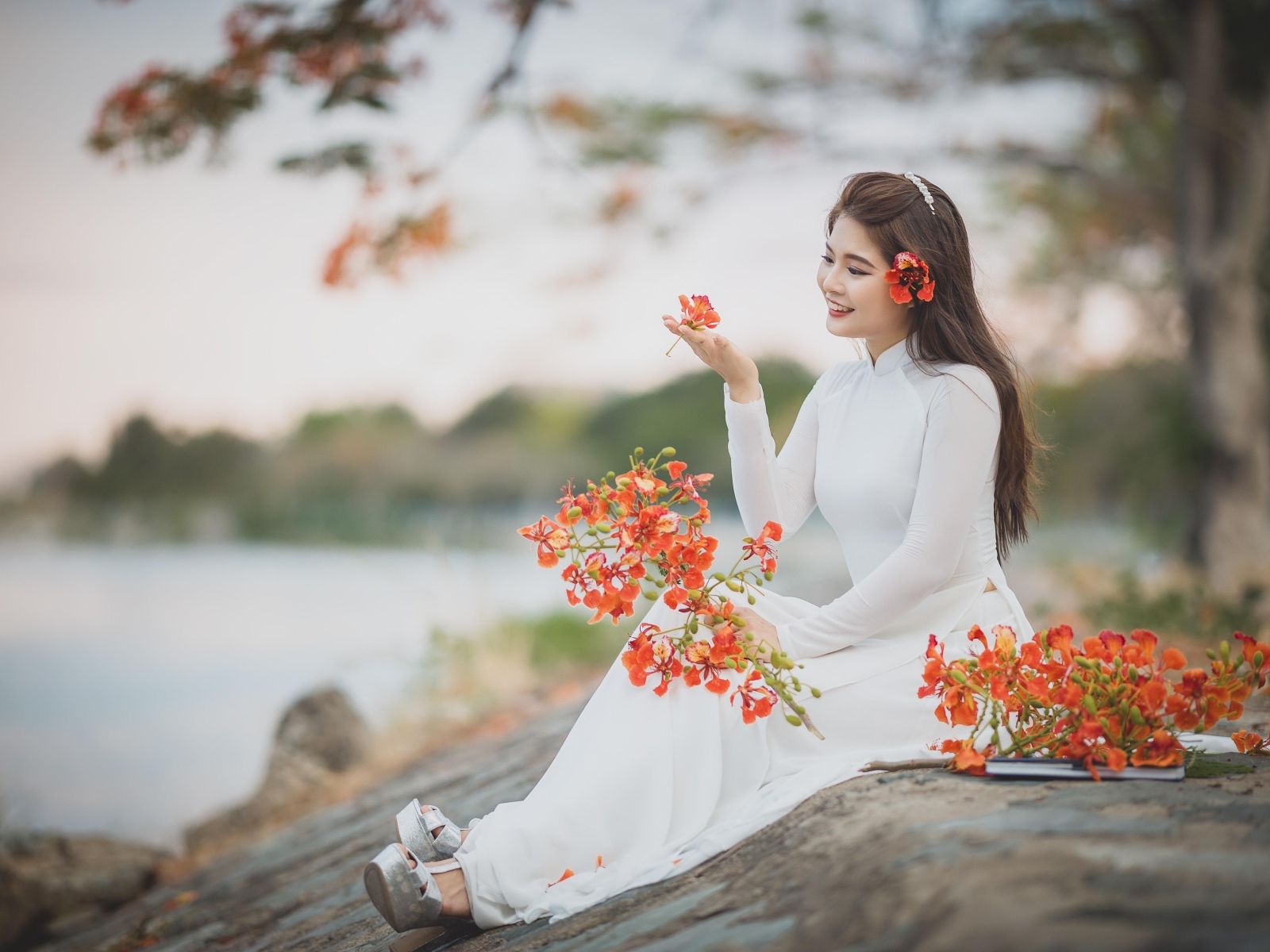 Красивая девушка азиатка в белом платье с цветами в руке