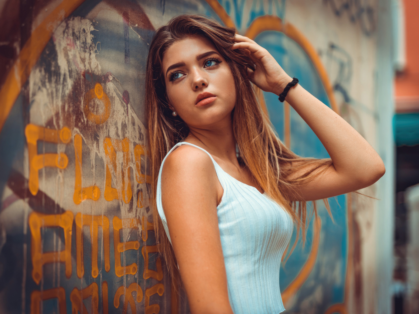 Красивая голубоглазая девушка стоит у стены