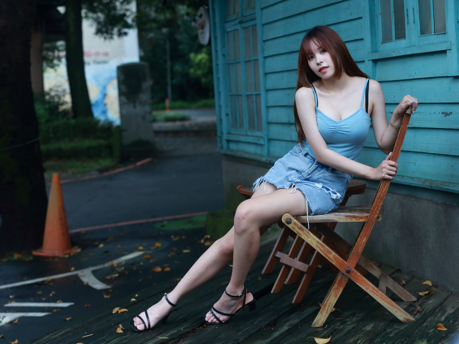 Красивая девушка сидит на стуле у дома