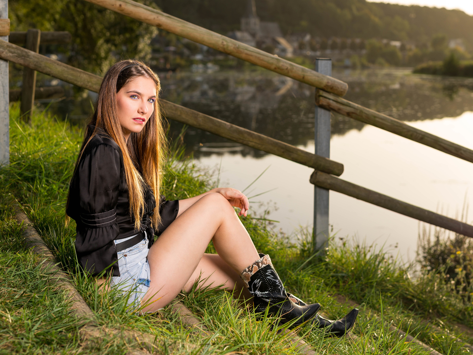 Красивая девушка сидит на берегу реки