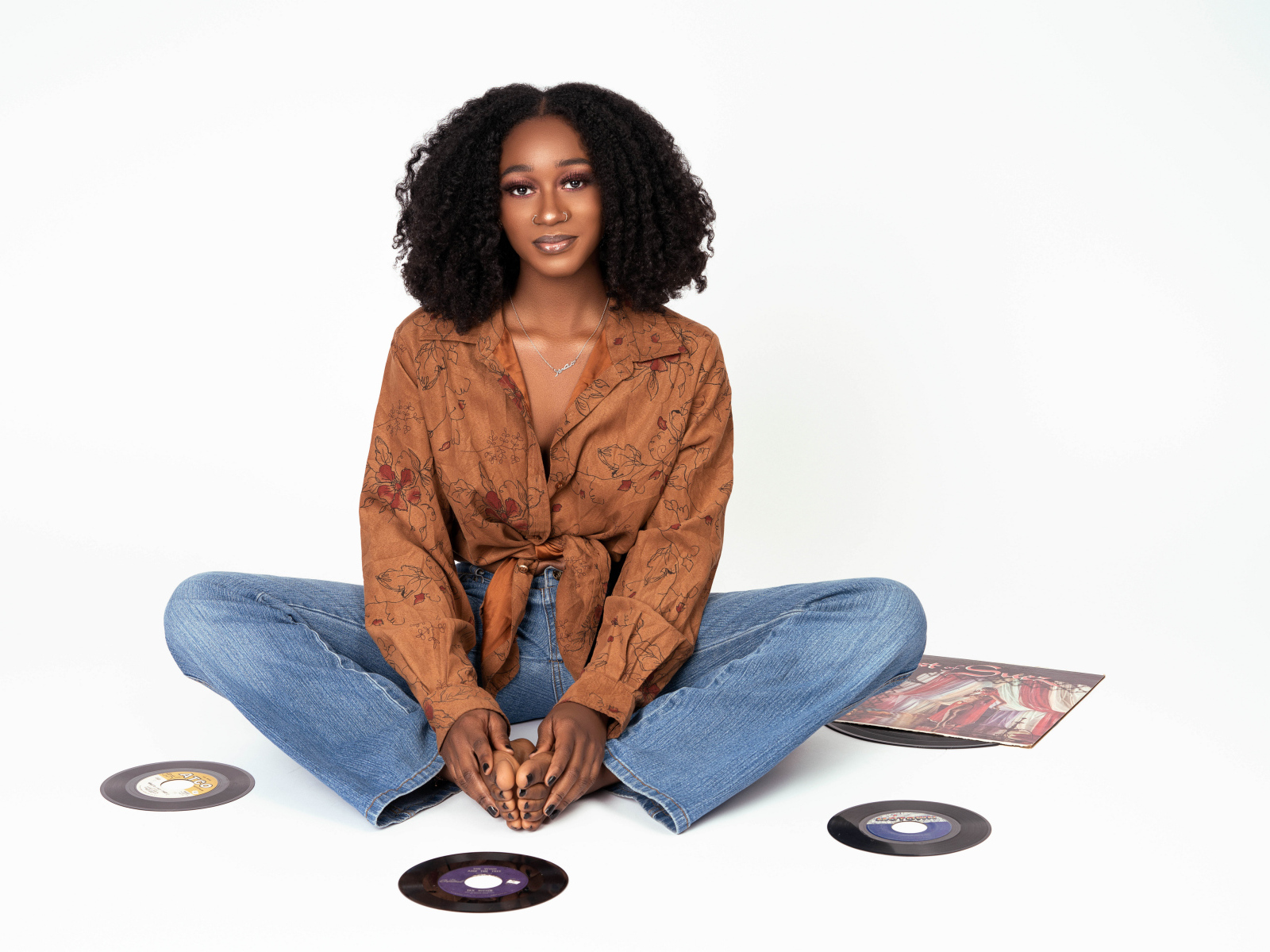 Темнокожая девушка сидит на белом фоне с пластинками