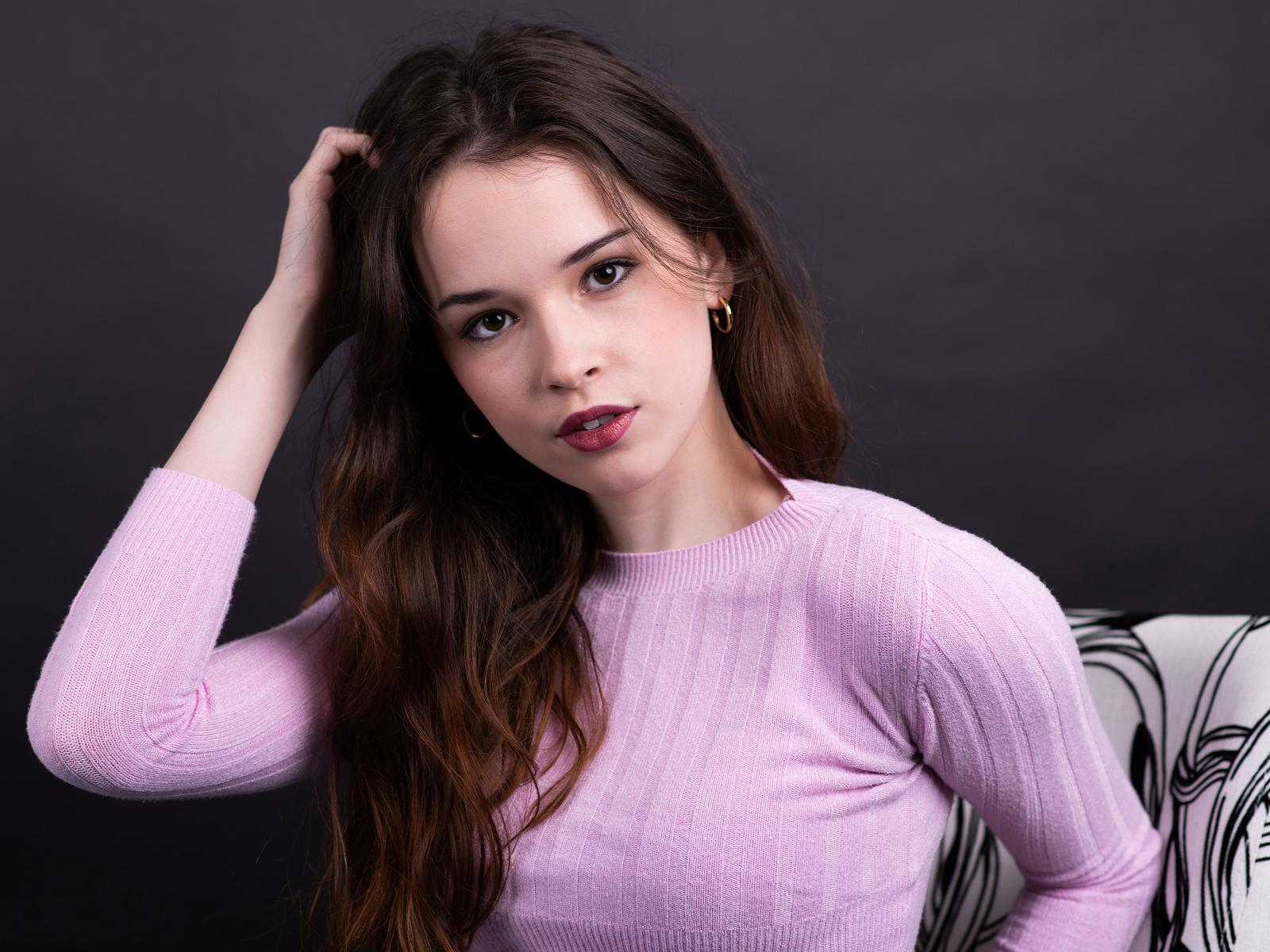 Длинноволосая шатенка в свитере с рукой в волосах
