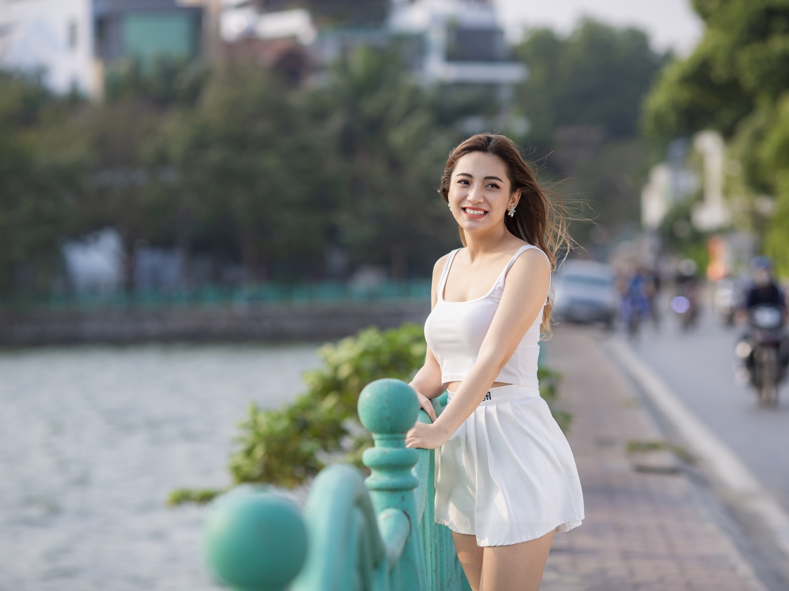 Улыбающаяся девушка азиатка в белом летнем костюме