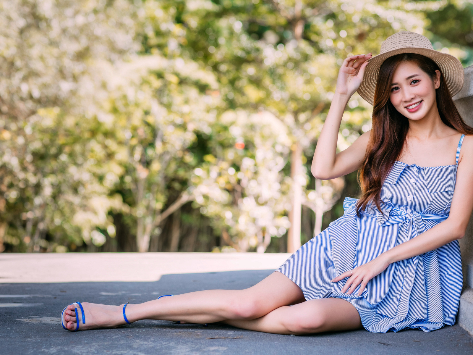 Улыбающаяся девушка азиатка сидит на асфальте