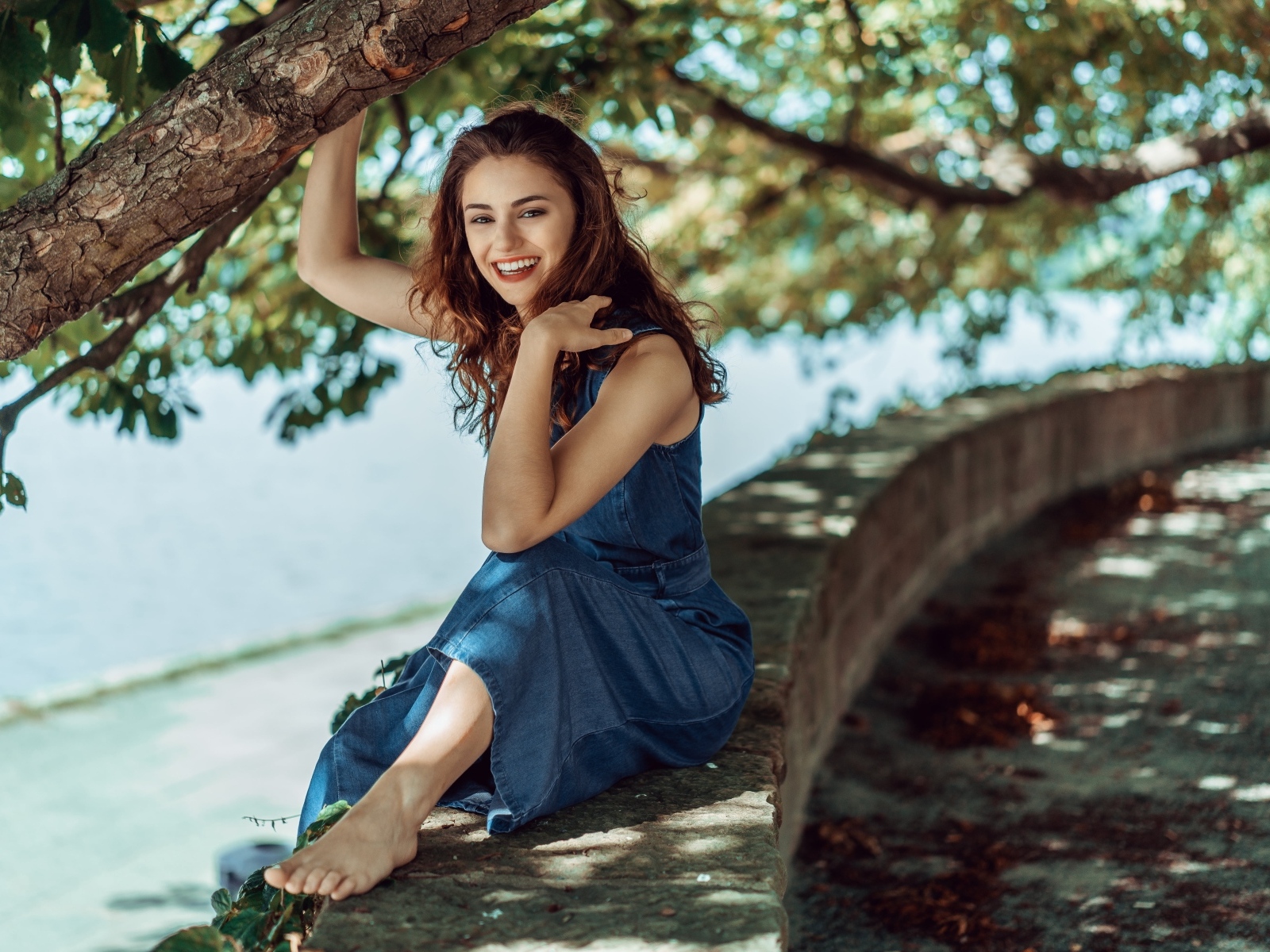 Улыбающаяся девушки сидит у дерева