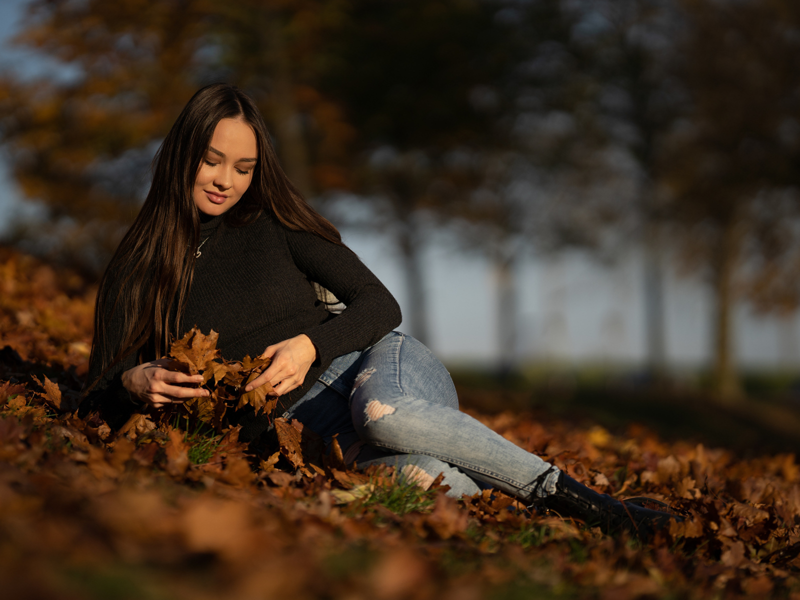 Молодая девушка лежит на сухих опавших листьях