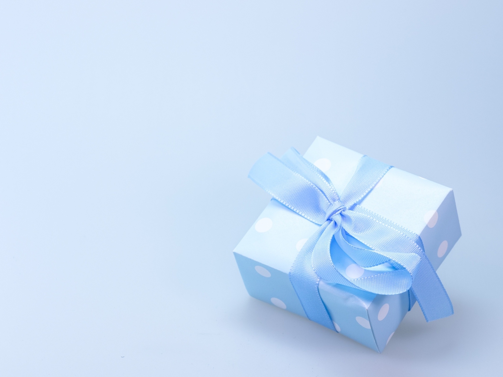 Коробка для подарка с голубой лентой на сером фоне