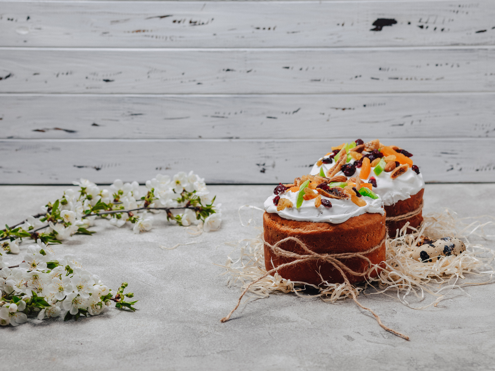 Красивые пасхальные куличи с веткой вишни на сером столе на Пасху