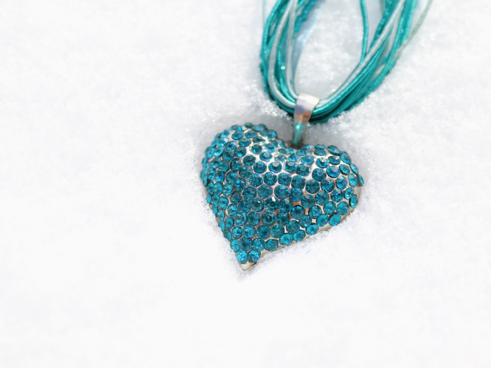 Голубой кулон в форме сердца на снегу