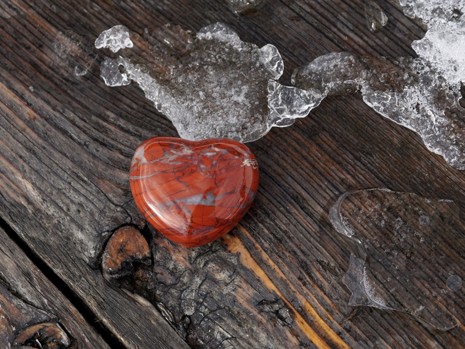 Сердце из камня на деревянной лавке с тающим снегом