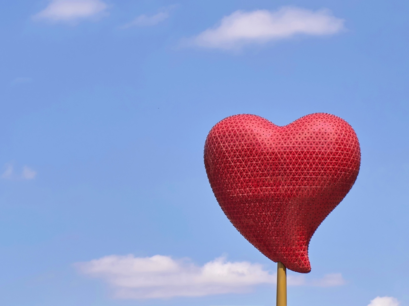 Красное сердце на палочке на фоне неба
