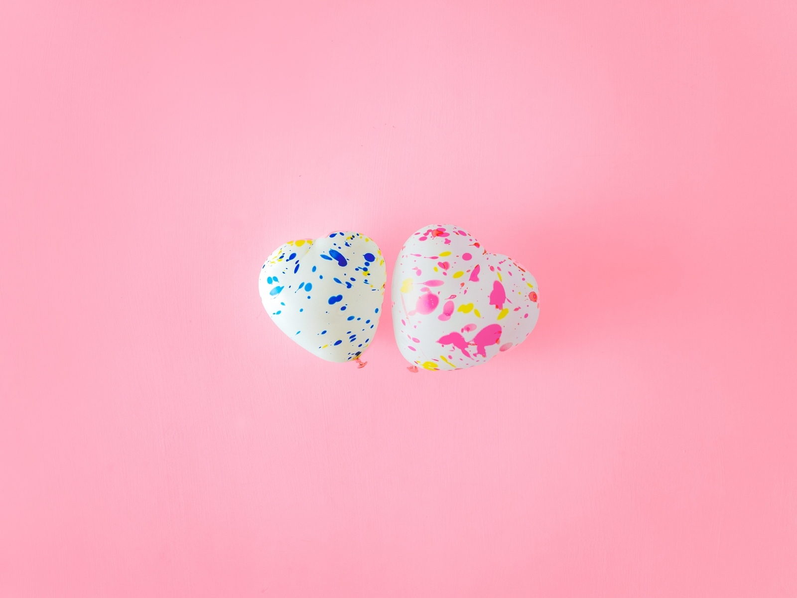 Два шарика в форме сердца на розовом фоне