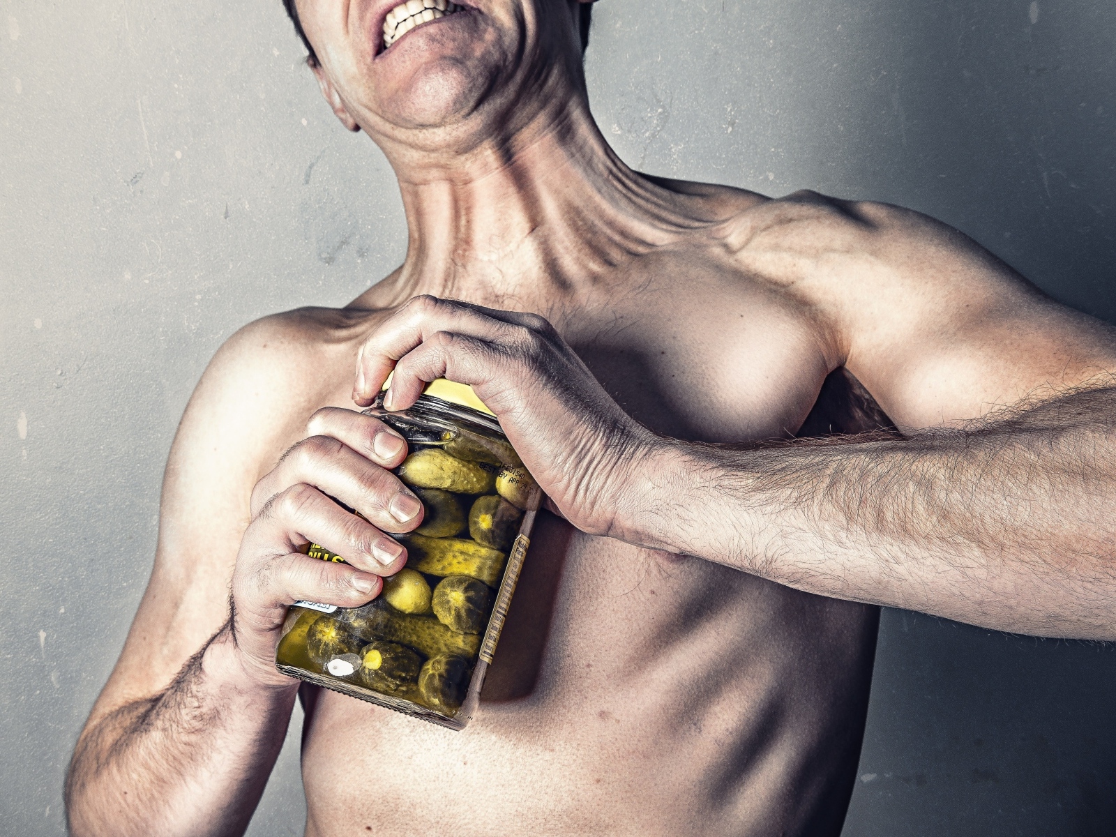 Мужчина открывает банку огурцов