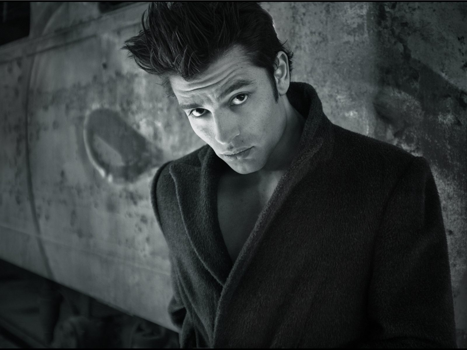 Красивый мужчина в черном пальто у стены