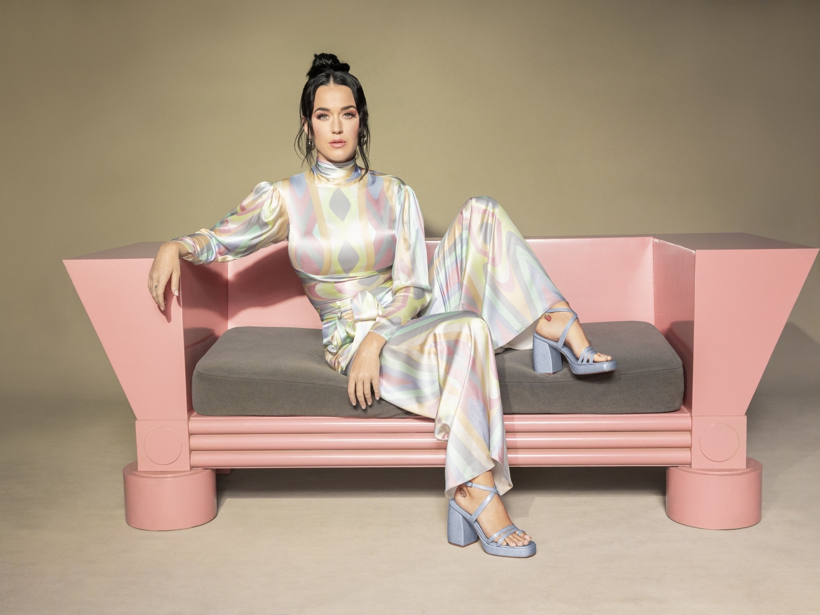 Певица Кэти Перри сидит на розовом диване