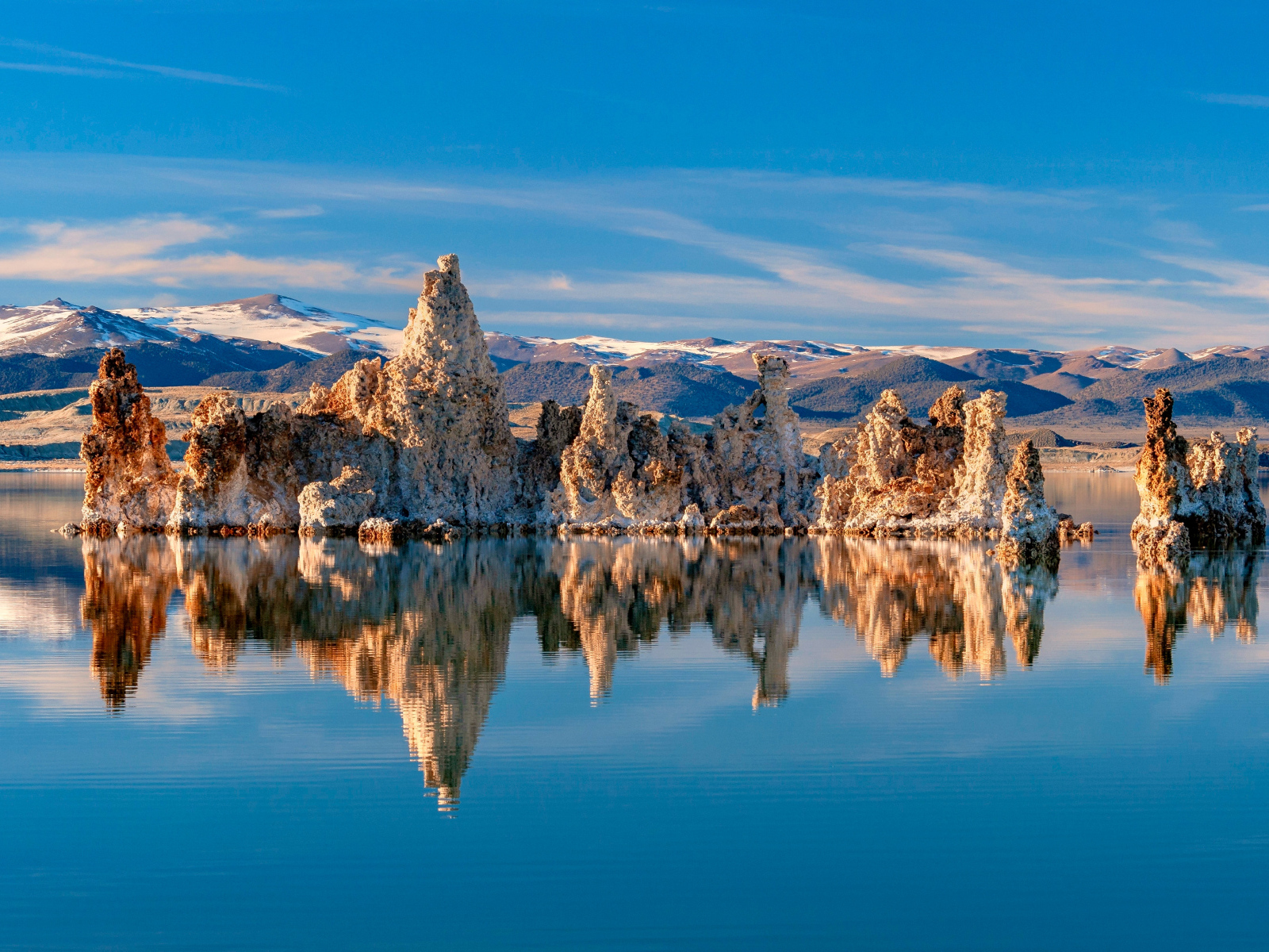 Острые скалы отражаются в тихой воде озера