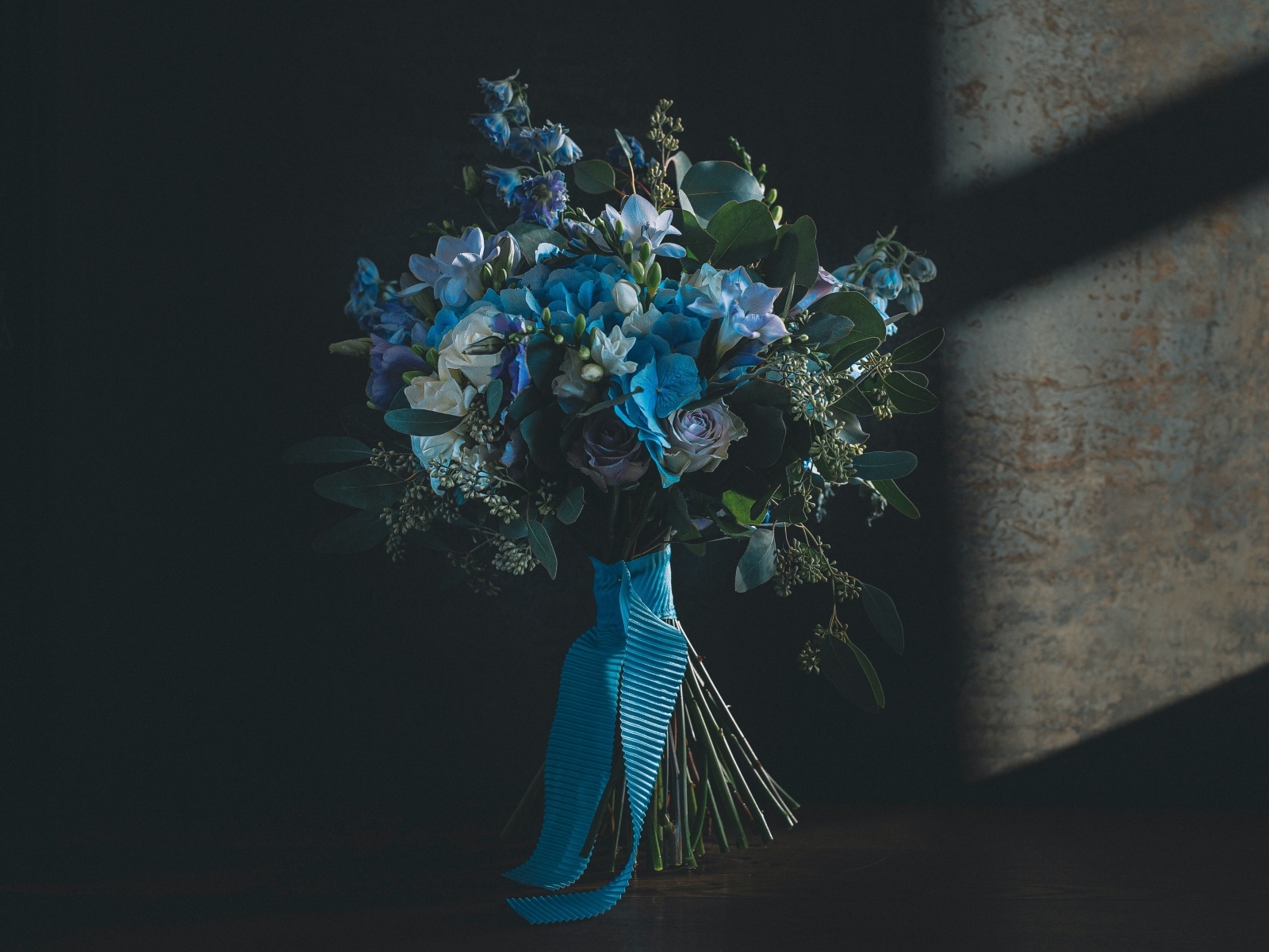 Красивый букет цветов с голубой лентой у стены