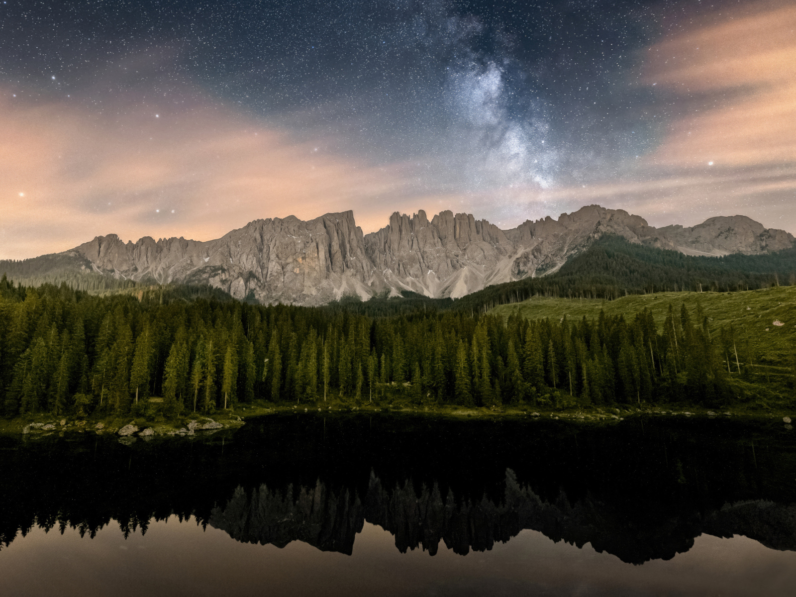 Млечный путь над горами и лесом отражающимися в воде