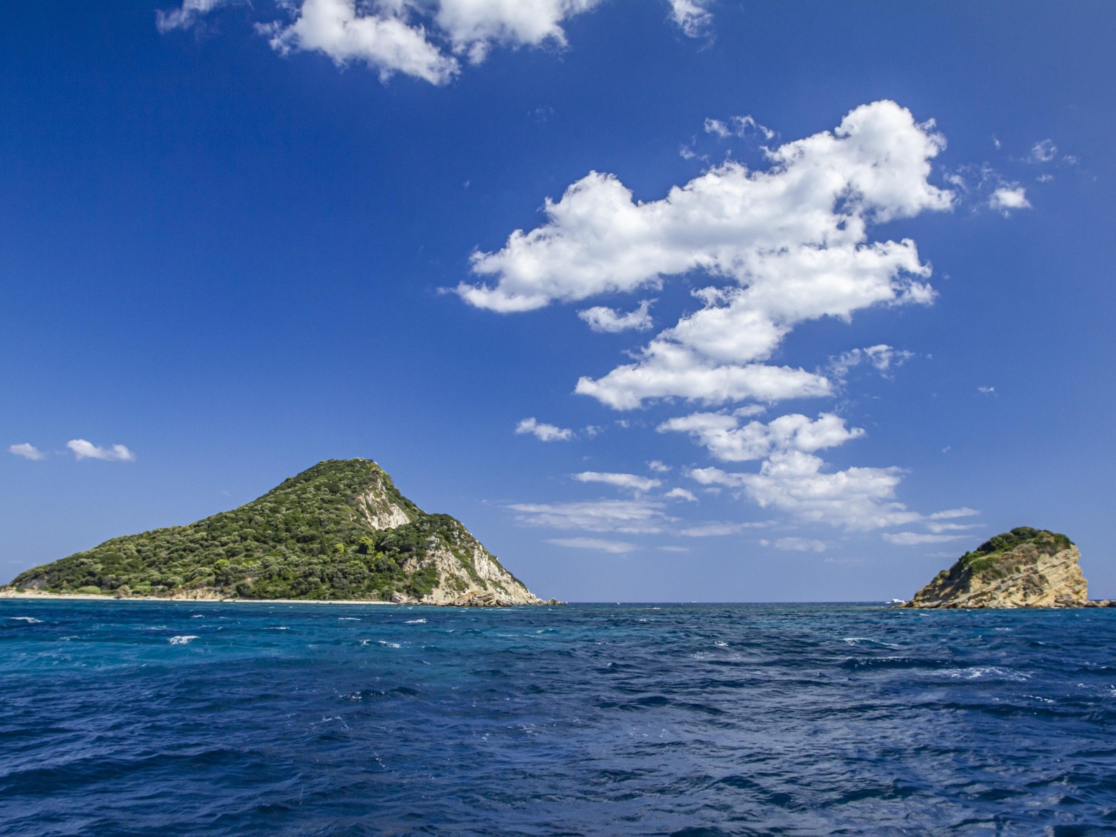 Покрытые зеленью горы в море под голубым небом