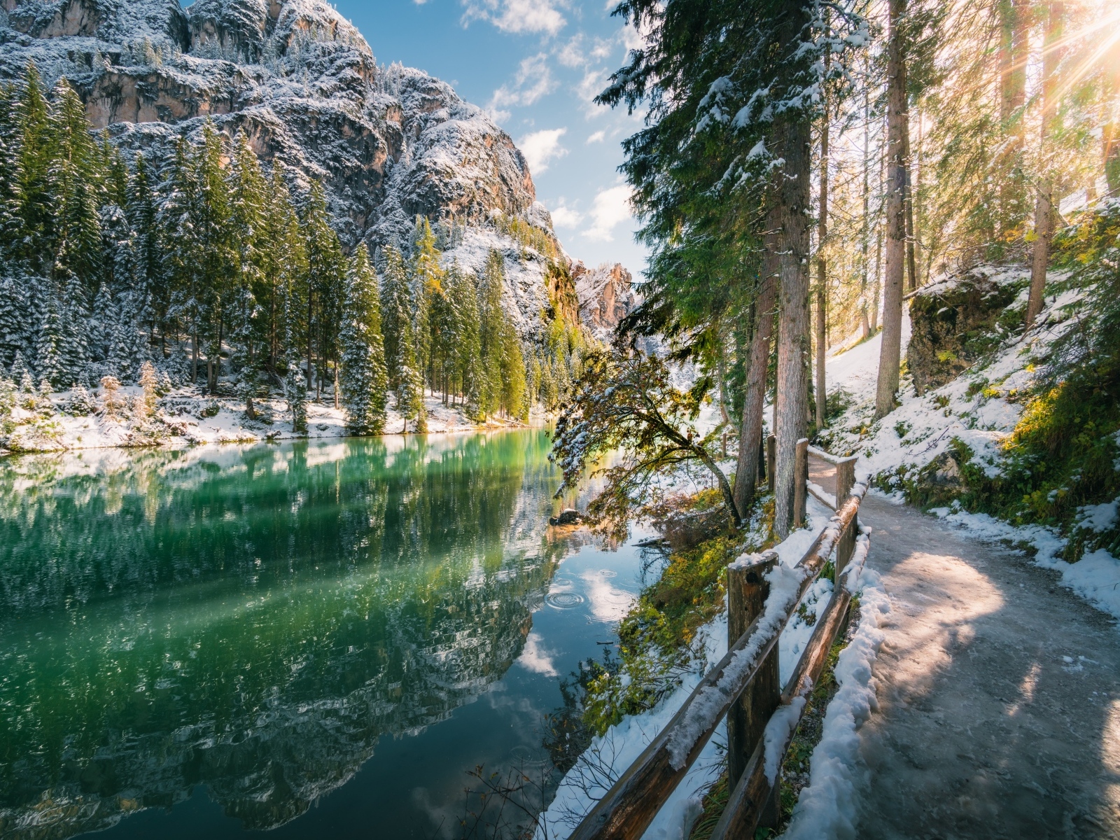 Заснеженная дорога у холодного горного озера в лесу