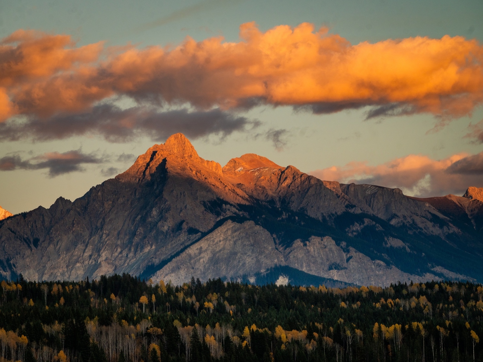 Солнце в облаках освещает вершину горы