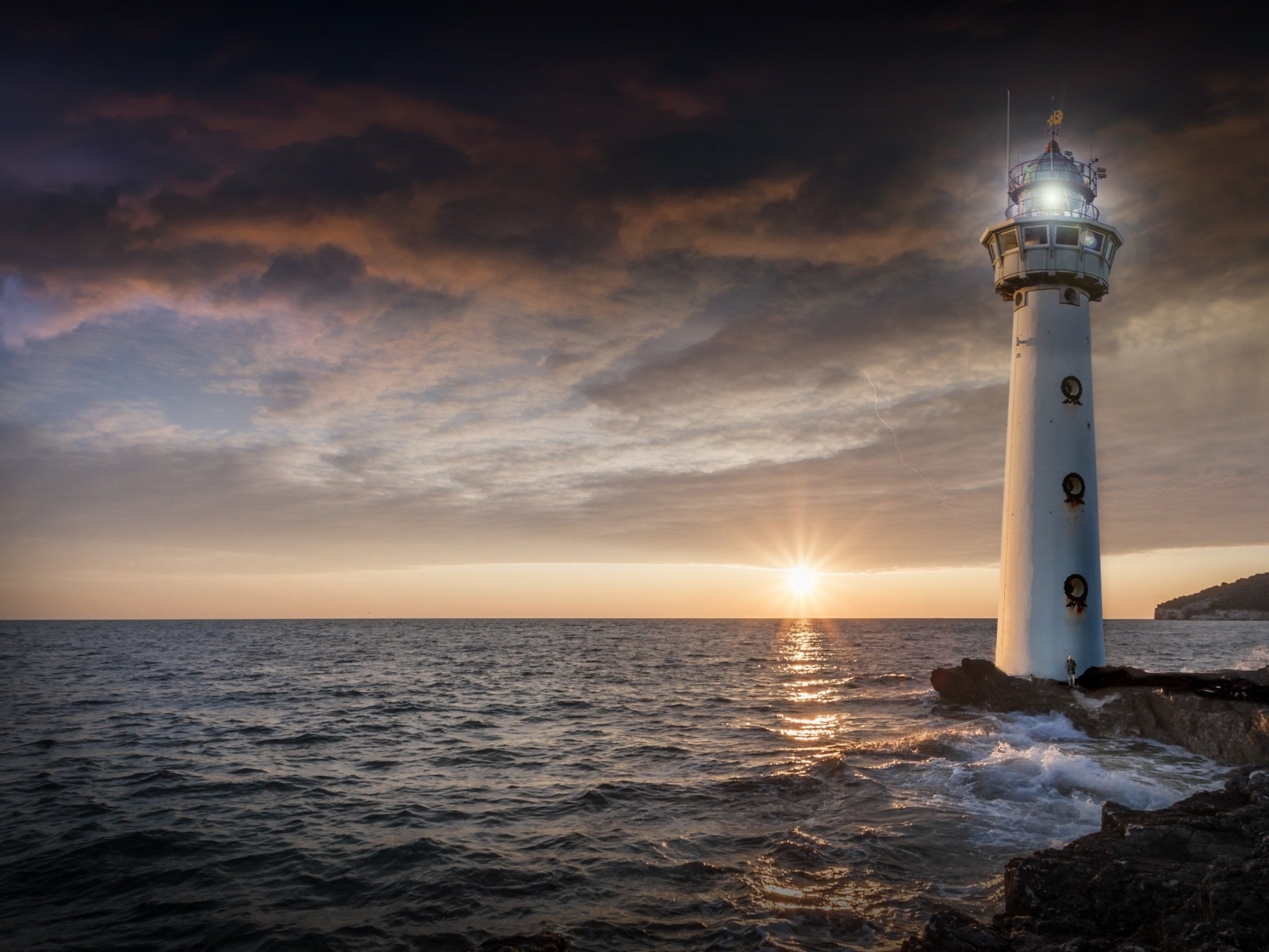 Высокий маяк на берегу моря на закате