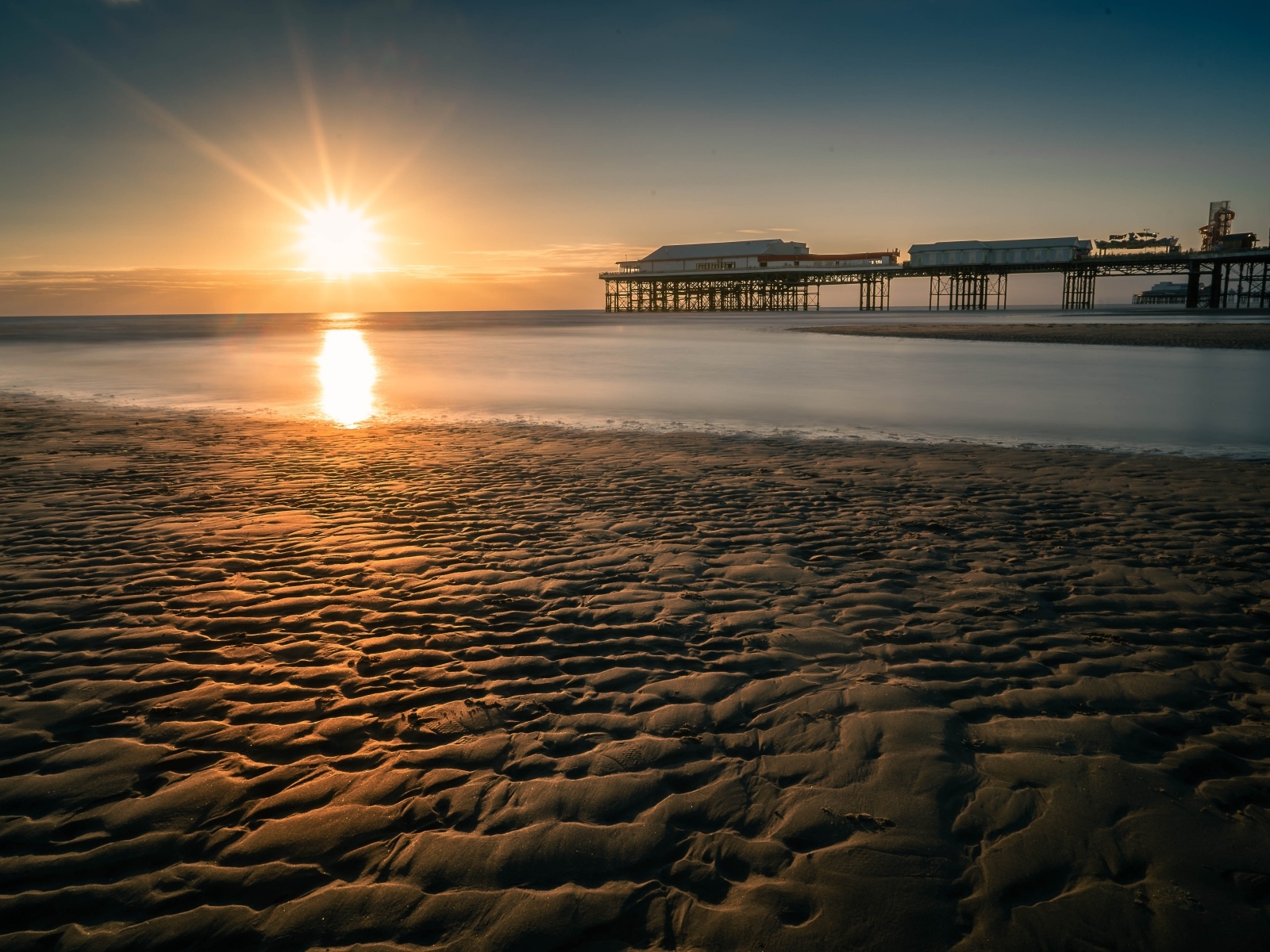 Мокрый песок на берегу моря на закате