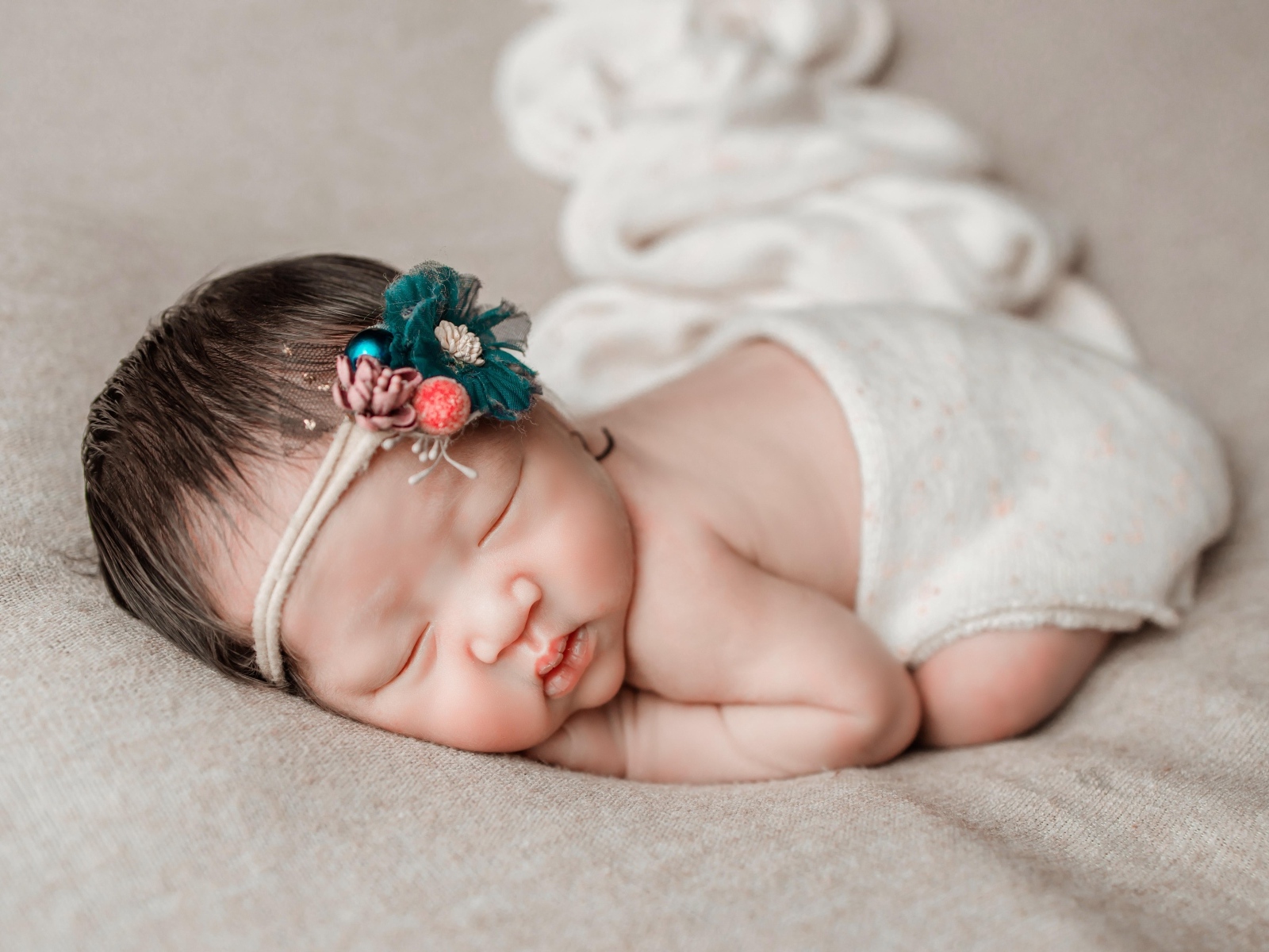 Новорожденная девочка азиатка спит на сером покрывале