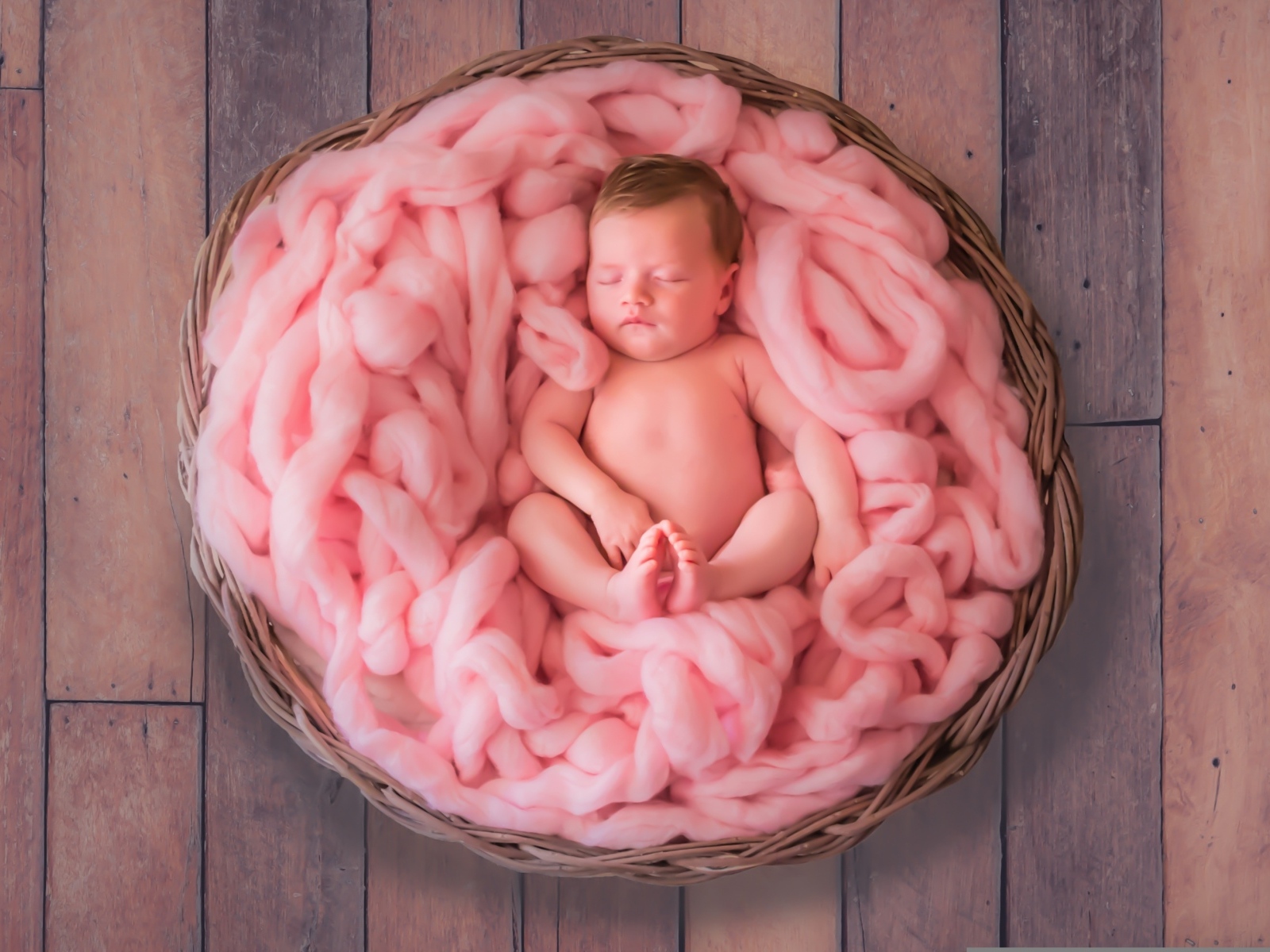 Ребенок спит в корзине с розовым покрывалом