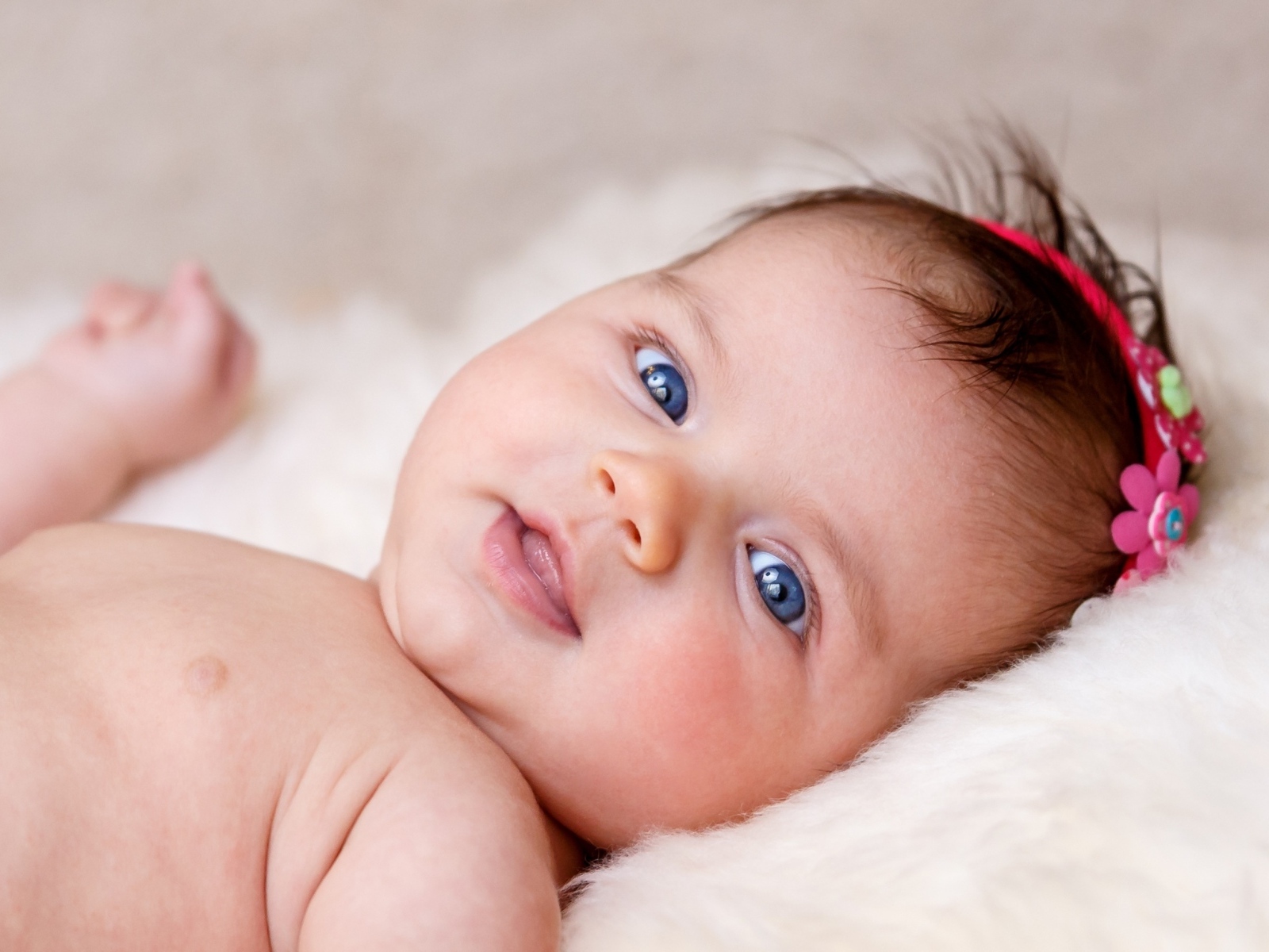 Голубоглазая новорожденная малышка с цветком на голове