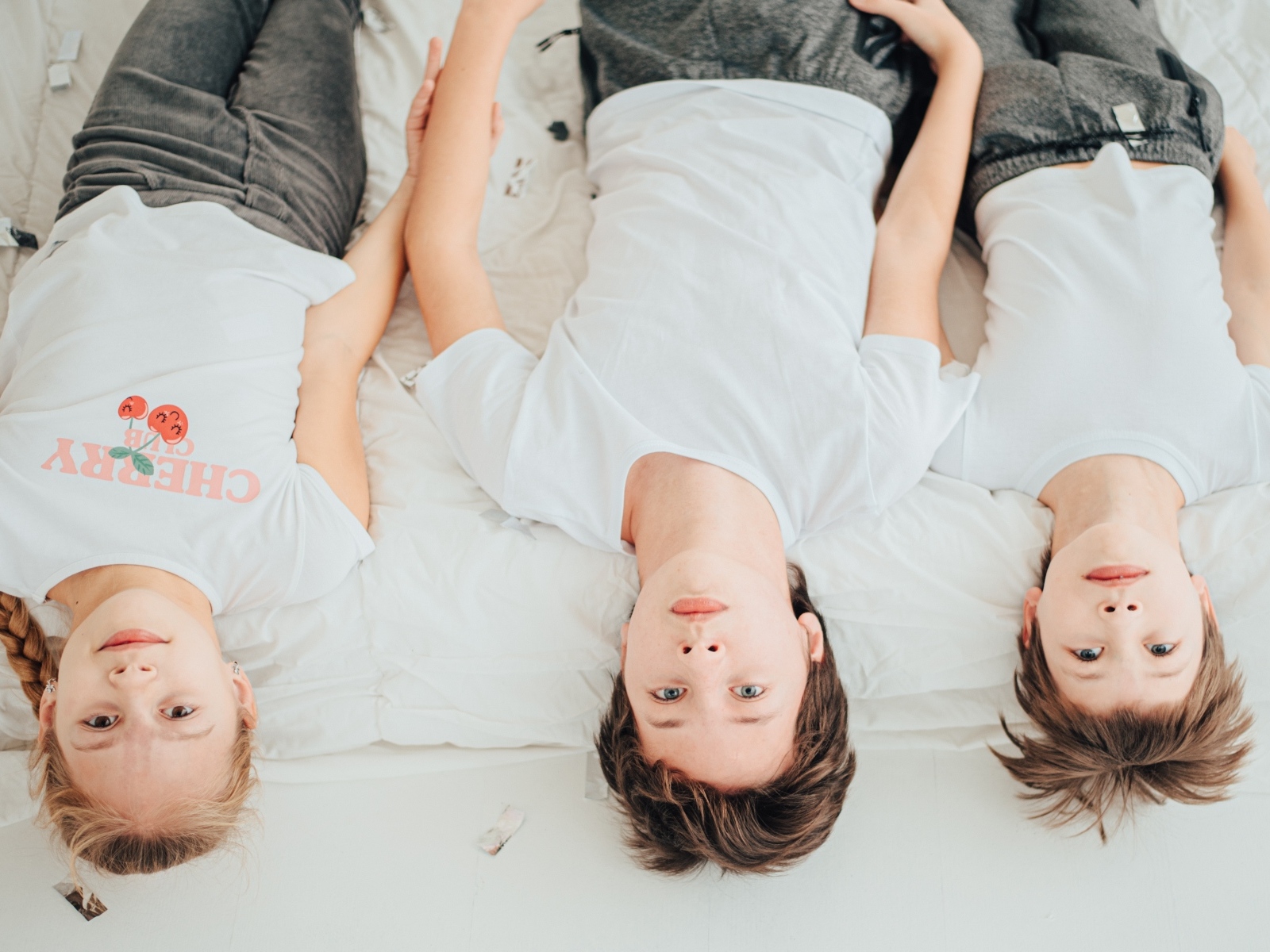 Дети в белых футболках лежат на кровати