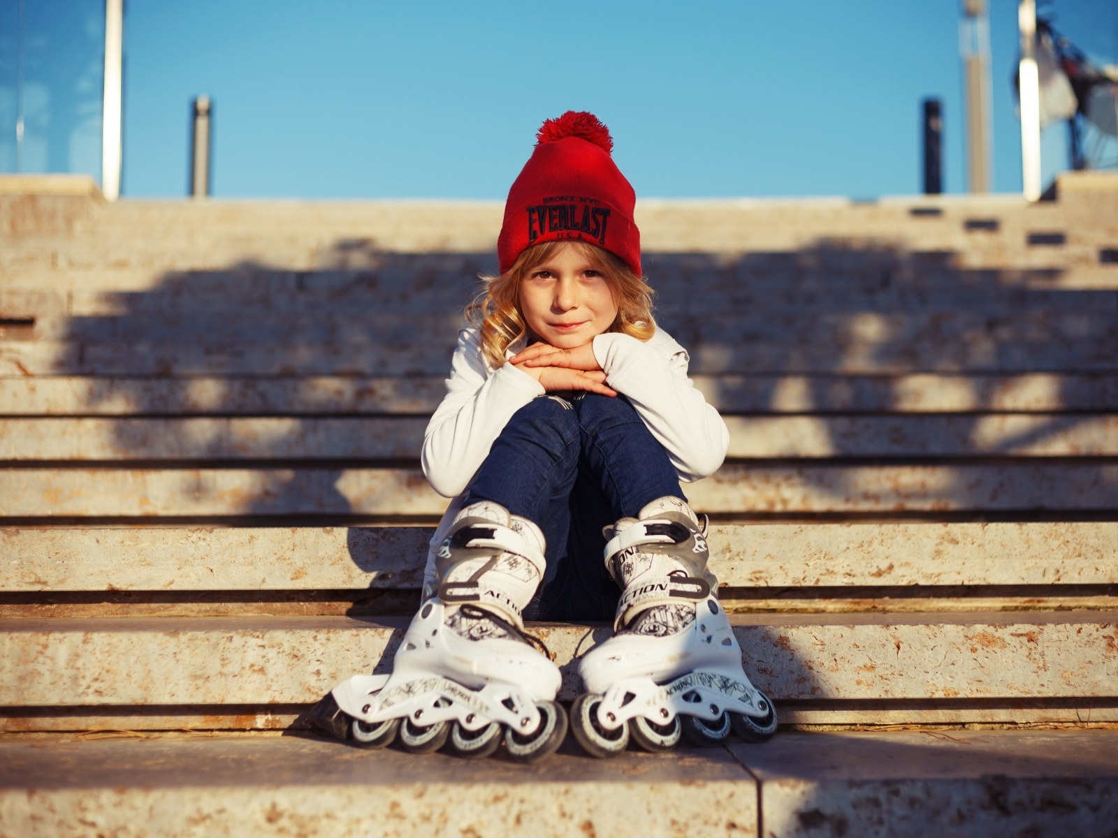 Девочка в роликах сидит на ступенях