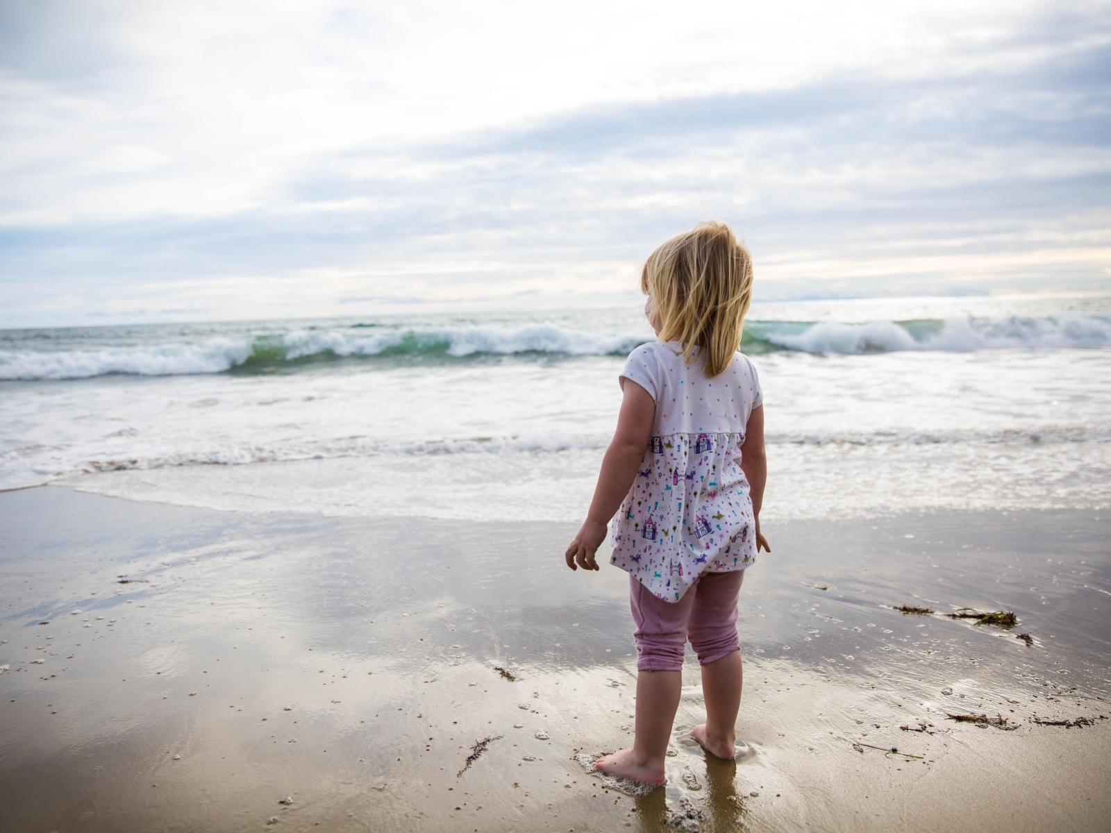 Маленькая девочка стоит на берегу моря