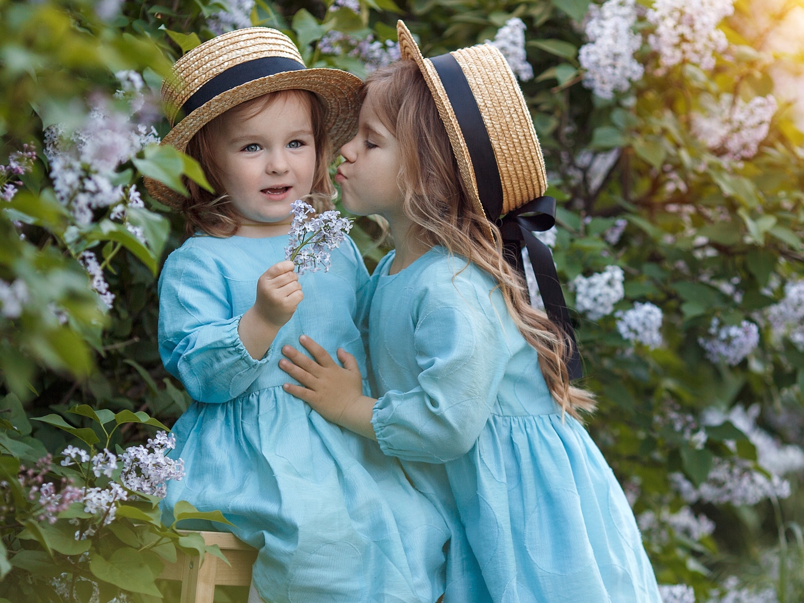 Две маленькие девочки в саду с сиренью