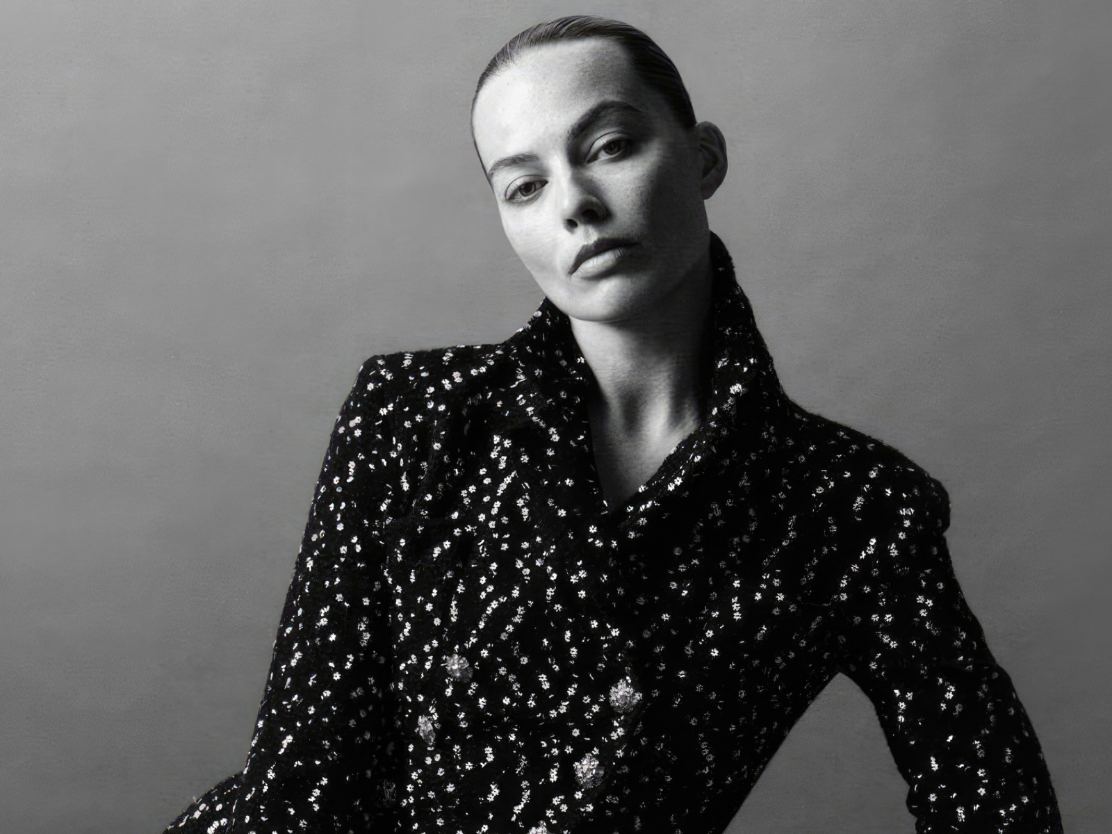 Грустная Марго Робби в блестящем пиджаке на сером фоне