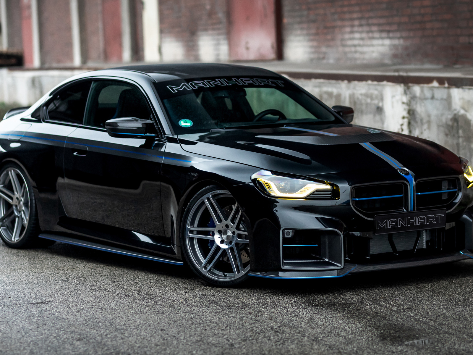 Черный автомобиль BMW M2 Manhart MH2 560 на сером фоне в городе