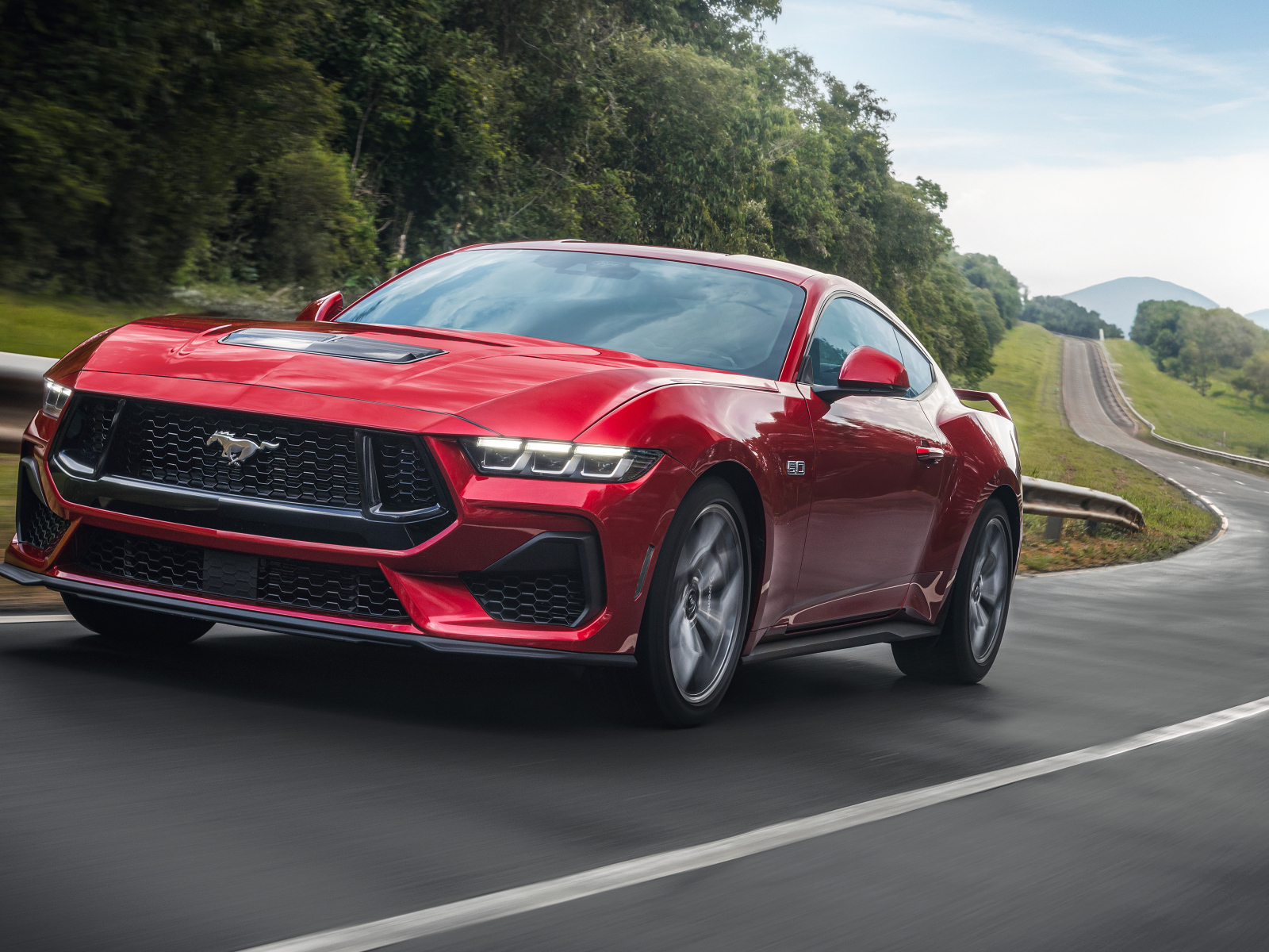 Красный автомобиль  Ford Mustang GT Performance 2024  года на дороге