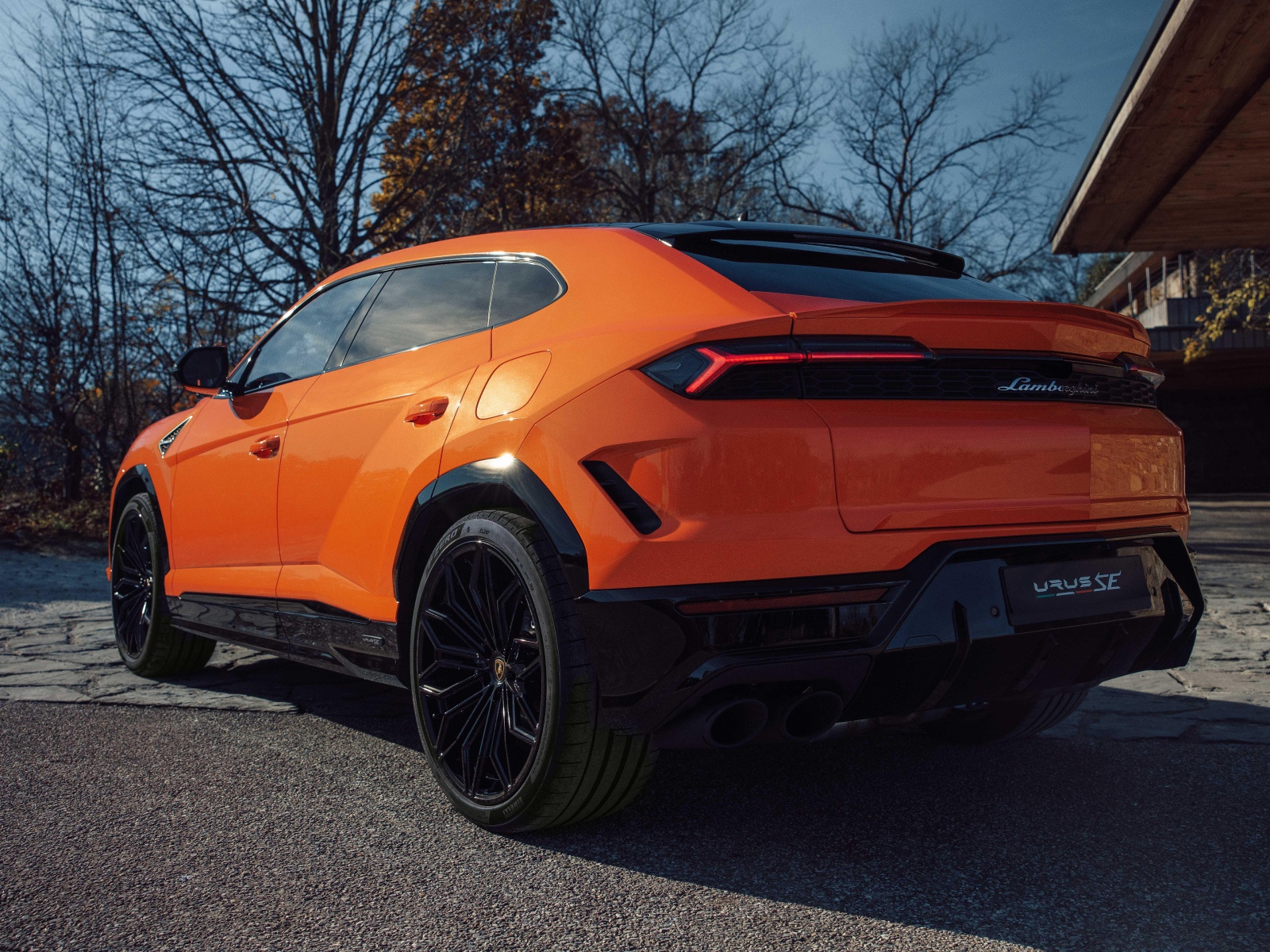 Вид сзади на оранжевый внедорожник Lamborghini Urus SE Plug-In Hybrid