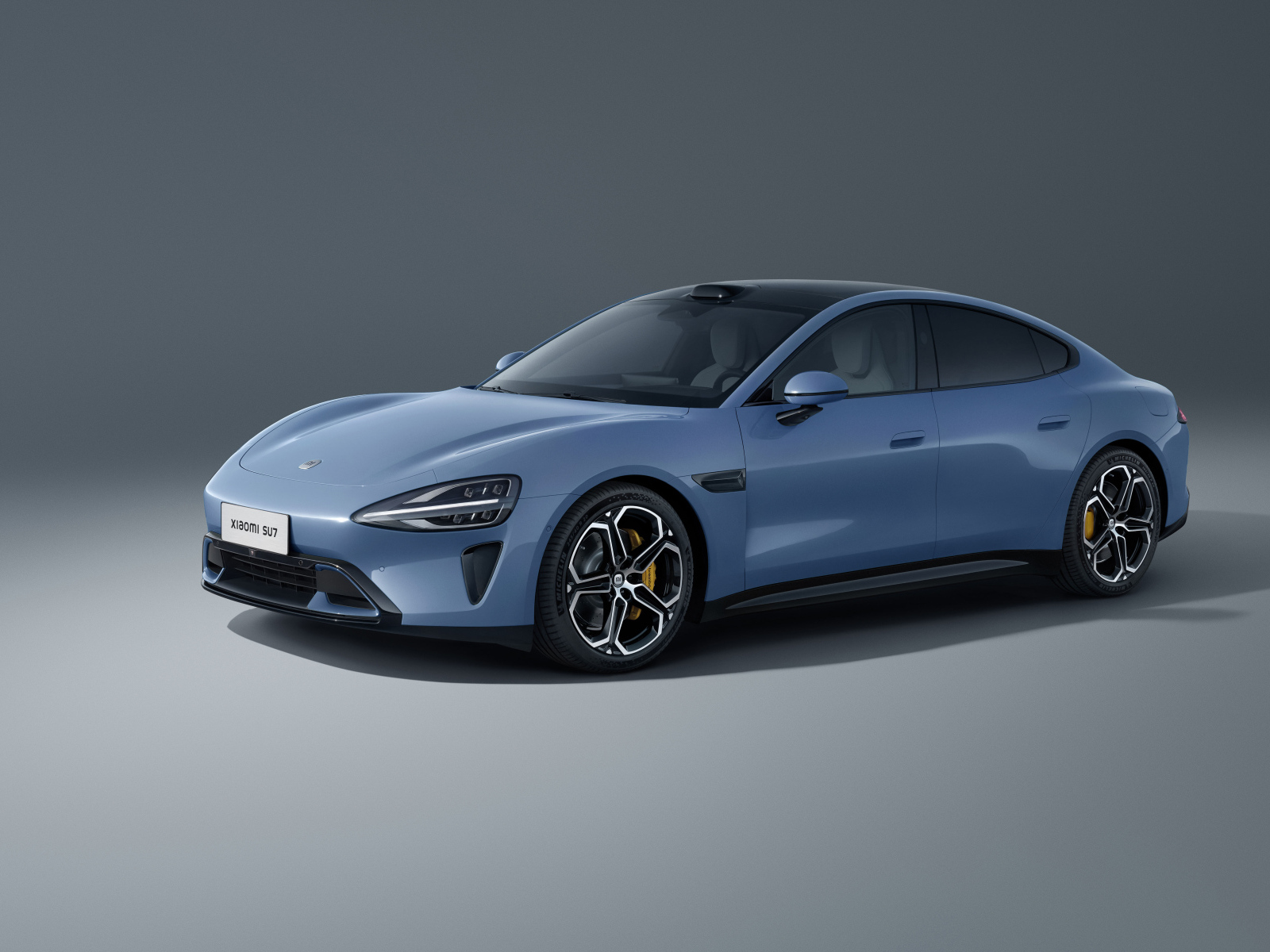 Автомобиль Xiaomi SU7 Max 2024 года на сером фоне